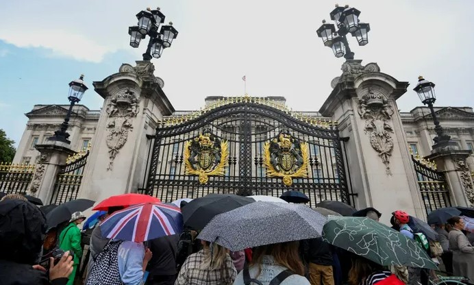 Люди собираются под зонтиками у Букингемского дворца в Лондоне